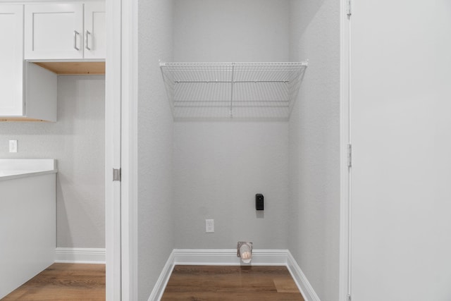 clothes washing area featuring wood-type flooring, cabinets, and hookup for an electric dryer