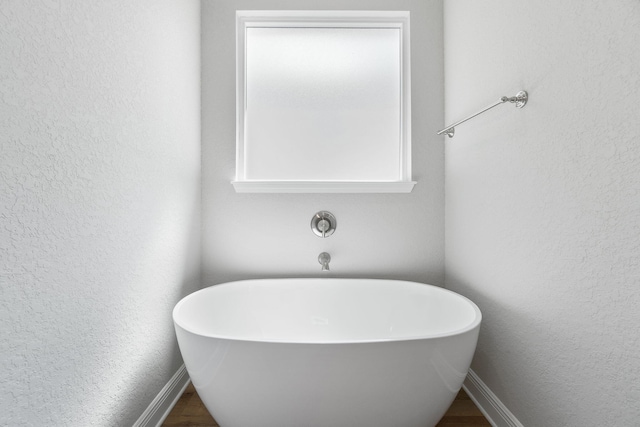 bathroom with hardwood / wood-style flooring and a tub to relax in