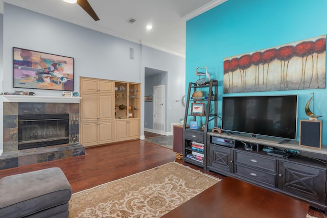 living room featuring ceiling fan, a fireplace, ornamental molding, and dark hardwood / wood-style floors