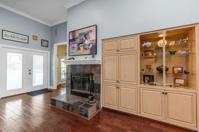 living room with french doors, ornamental molding, dark hardwood / wood-style flooring, a towering ceiling, and a fireplace