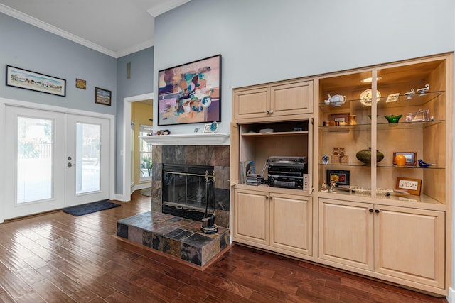 living room featuring dark wood-type flooring, french doors, crown molding, a tile fireplace, and a towering ceiling