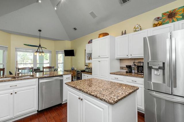 kitchen with white cabinetry, decorative light fixtures, stainless steel appliances, and a center island