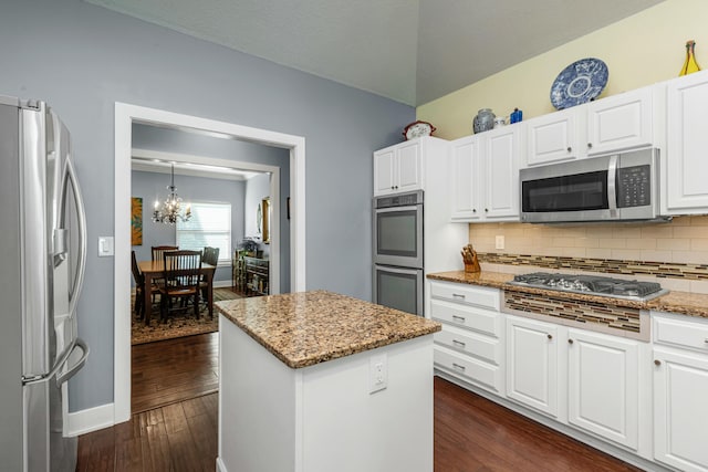 kitchen with stainless steel appliances, white cabinetry, light stone countertops, and a center island