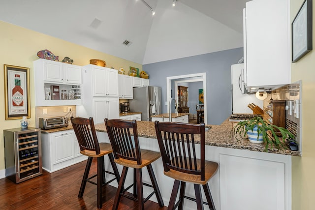 kitchen with stainless steel refrigerator with ice dispenser, wine cooler, kitchen peninsula, dark stone counters, and white cabinets