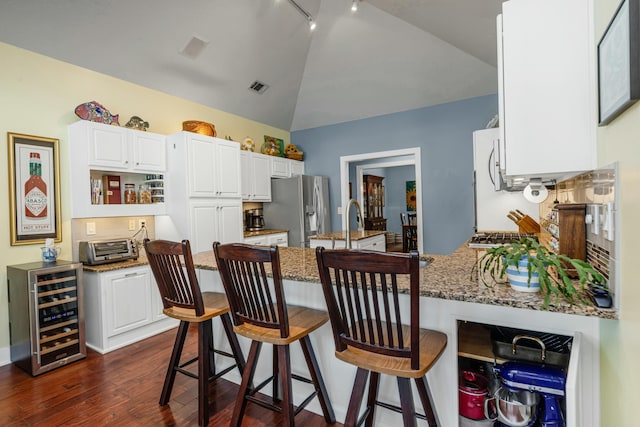 kitchen featuring vaulted ceiling, white cabinetry, wine cooler, dark stone counters, and stainless steel refrigerator with ice dispenser