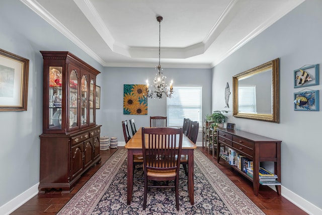 dining area featuring dark wood-type flooring, a tray ceiling, crown molding, and a notable chandelier