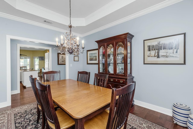 dining space featuring ornamental molding, dark hardwood / wood-style flooring, and a raised ceiling