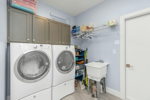 laundry area featuring light hardwood / wood-style floors, washing machine and dryer, and cabinets