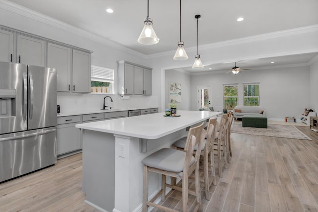 kitchen with gray cabinetry, a kitchen island, open floor plan, light countertops, and appliances with stainless steel finishes