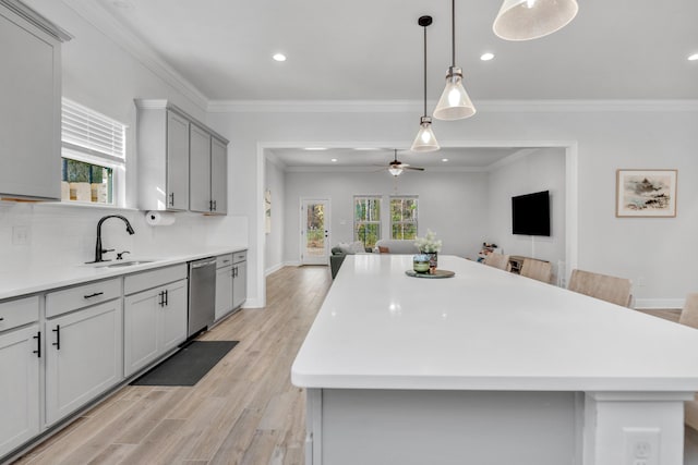 kitchen featuring a center island, light countertops, gray cabinetry, open floor plan, and a sink