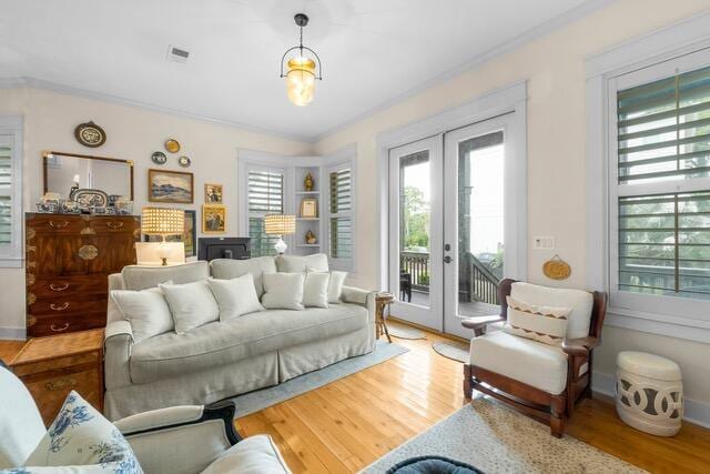 living room with wood-type flooring, ornamental molding, and french doors