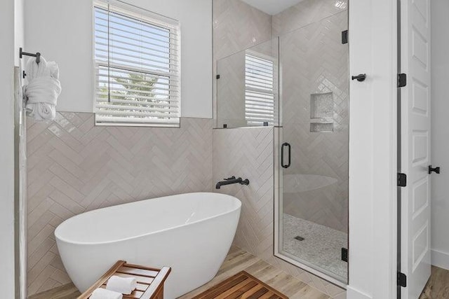 bathroom featuring hardwood / wood-style floors, separate shower and tub, and tile walls