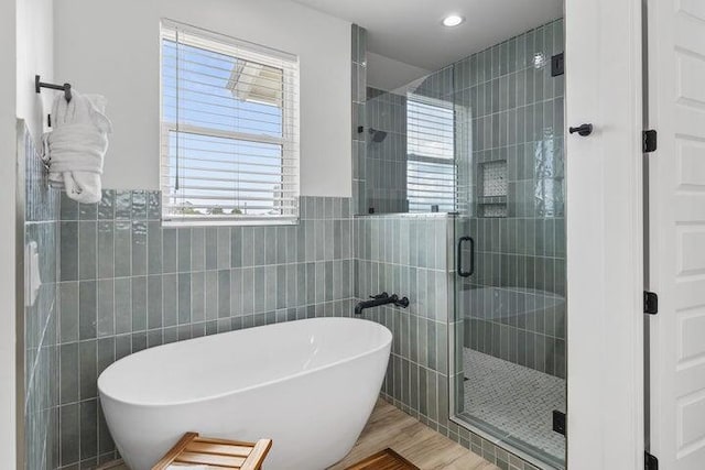 bathroom featuring hardwood / wood-style flooring, separate shower and tub, and tile walls