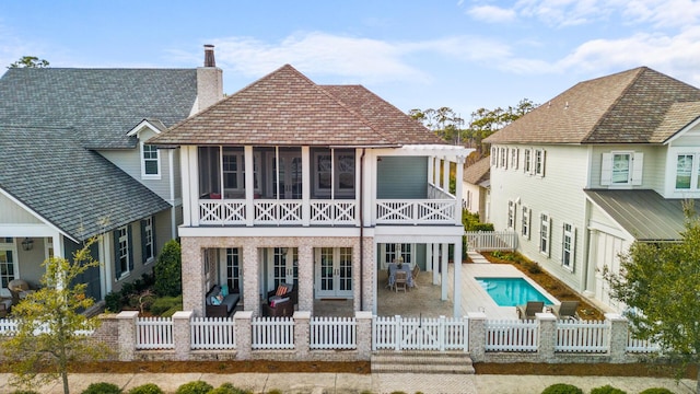 rear view of property featuring a fenced in pool, a sunroom, and a patio