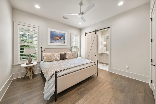 bedroom featuring dark hardwood / wood-style floors, ceiling fan, a barn door, and multiple windows