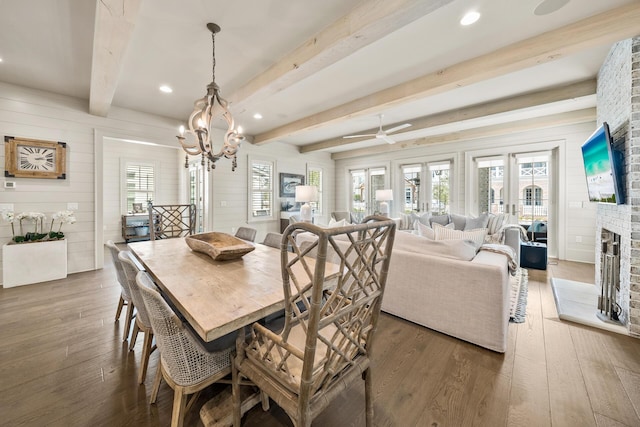 dining space with a fireplace, beam ceiling, and wood-type flooring