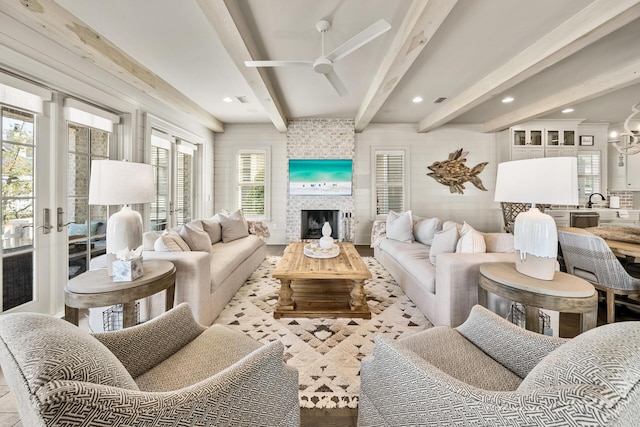 living room featuring ceiling fan, sink, a fireplace, and beam ceiling