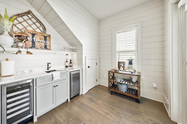 bar featuring wine cooler, fridge, dark hardwood / wood-style floors, light stone countertops, and white cabinets