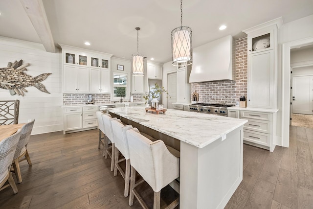 kitchen with premium range hood, a center island, dark hardwood / wood-style floors, white cabinets, and stove