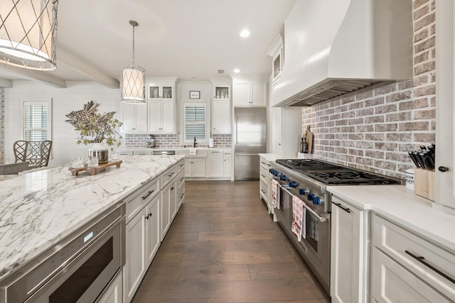 kitchen with dark wood-type flooring, custom exhaust hood, white cabinetry, pendant lighting, and decorative backsplash