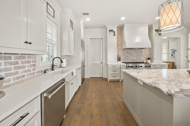 kitchen with high quality appliances, decorative light fixtures, custom range hood, and white cabinets