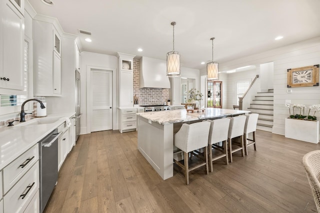 kitchen featuring premium range hood, hanging light fixtures, light hardwood / wood-style floors, white cabinets, and a kitchen island