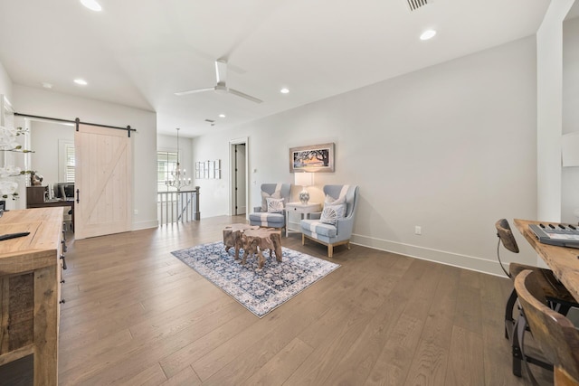 sitting room featuring ceiling fan, wood-type flooring, and a barn door