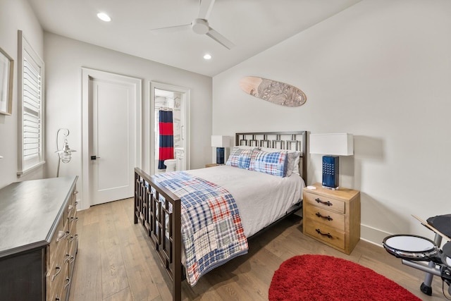 bedroom featuring multiple windows, ceiling fan, connected bathroom, and light wood-type flooring