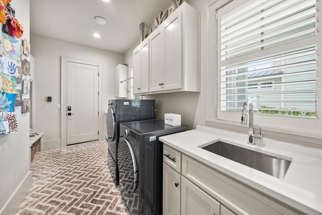 laundry area featuring cabinets, washing machine and clothes dryer, and sink