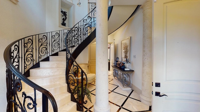 stairs with a towering ceiling and decorative columns