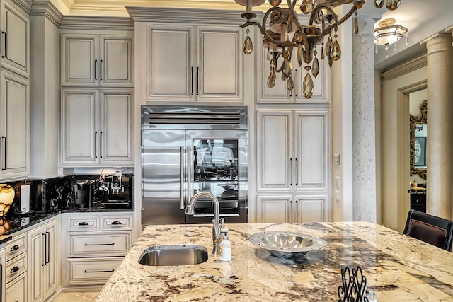 kitchen featuring light stone counters, a kitchen bar, high end fridge, and sink