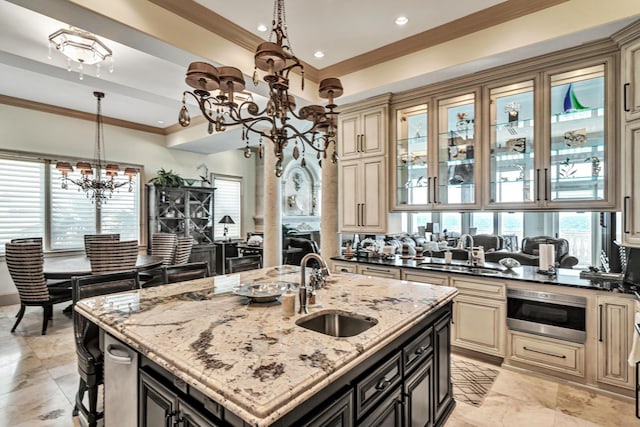 kitchen with sink, dark stone counters, a chandelier, and a center island with sink