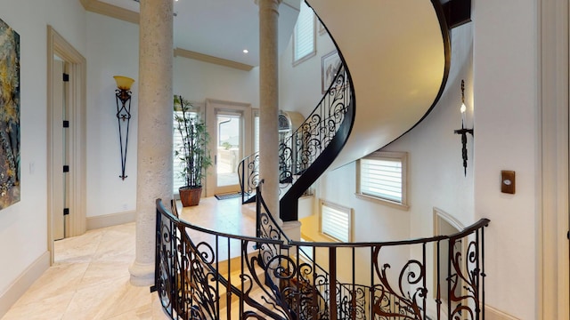 interior space with crown molding, a towering ceiling, and decorative columns