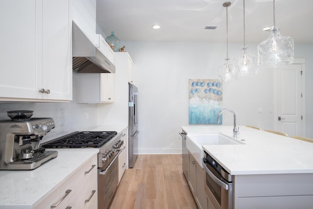 kitchen featuring a center island with sink, decorative backsplash, extractor fan, high quality appliances, and light wood-type flooring