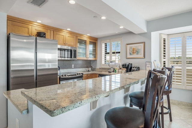 kitchen featuring light stone countertops, appliances with stainless steel finishes, a breakfast bar, and sink