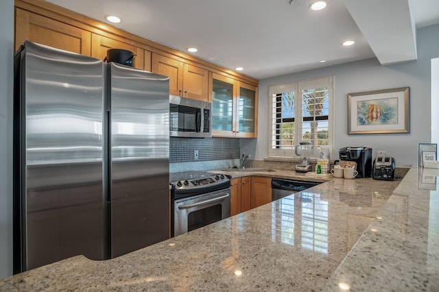 kitchen featuring stainless steel appliances, sink, backsplash, and light stone counters