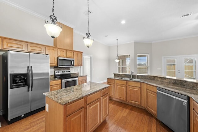 kitchen featuring crown molding, appliances with stainless steel finishes, sink, and pendant lighting