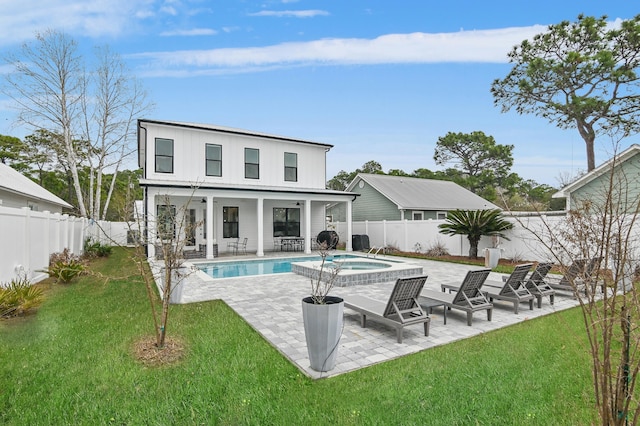 rear view of property featuring ceiling fan, a pool with hot tub, a patio, and a lawn