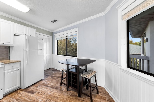 kitchen featuring white cabinetry, white fridge, crown molding, light stone countertops, and light hardwood / wood-style flooring