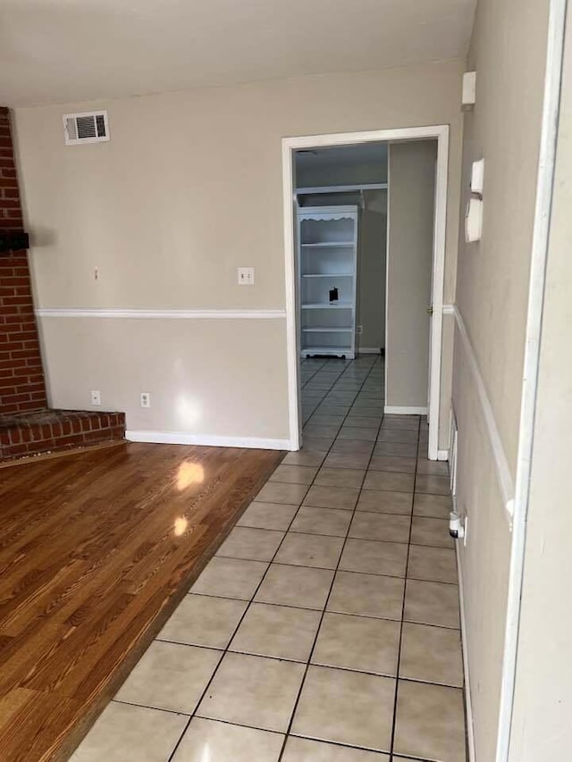 hall featuring light wood-style floors, baseboards, and visible vents