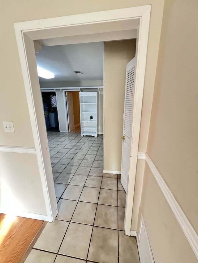 corridor with baseboards and light tile patterned floors