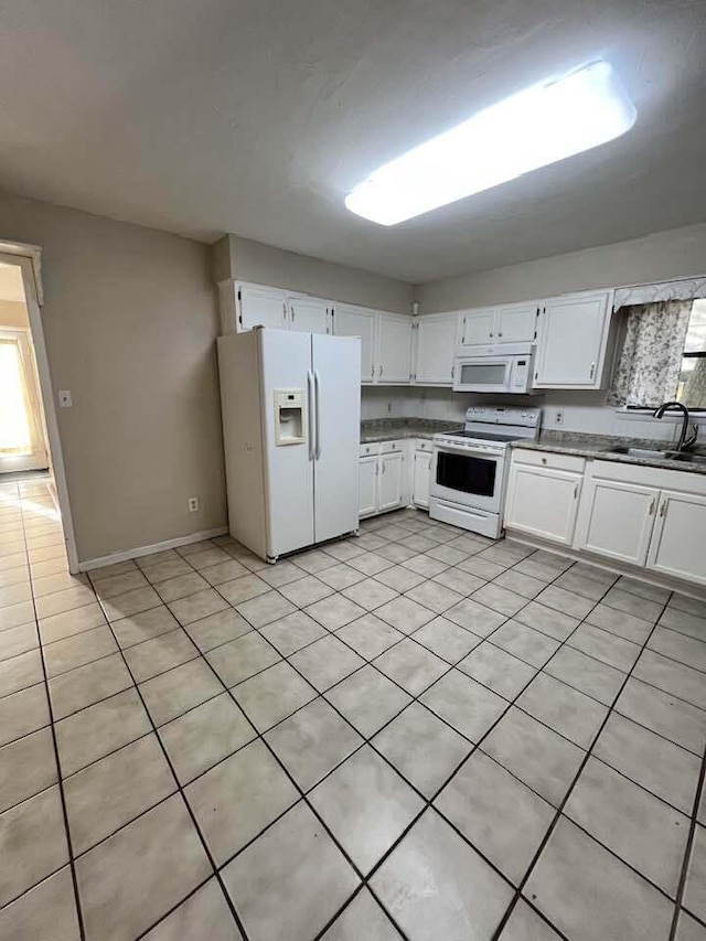 kitchen with baseboards, white appliances, a sink, and white cabinets