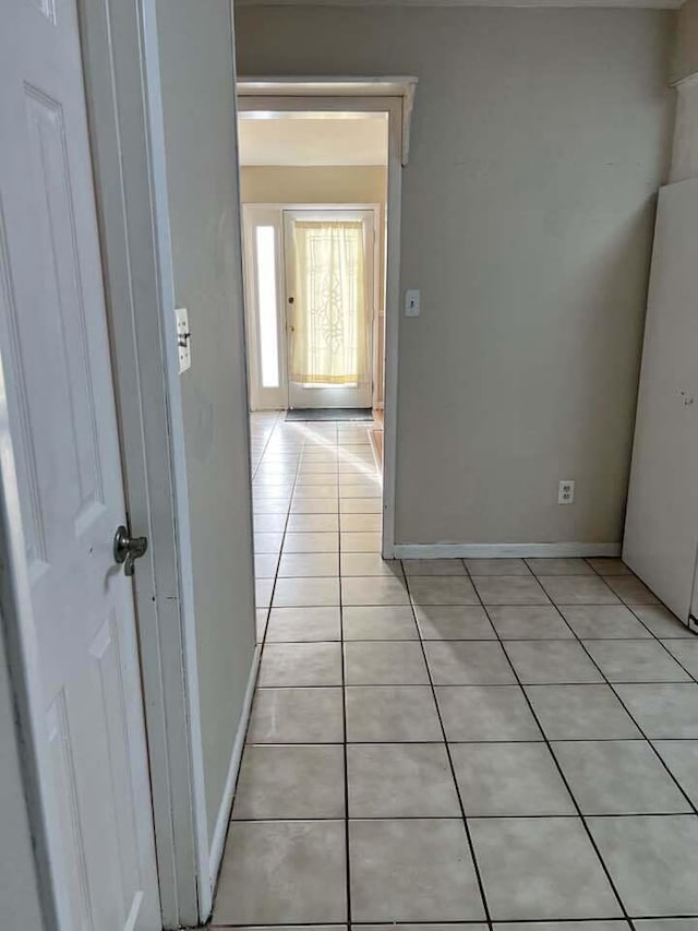 corridor featuring light tile patterned floors and baseboards