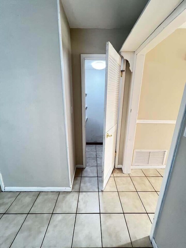 hall featuring visible vents, baseboards, and light tile patterned floors