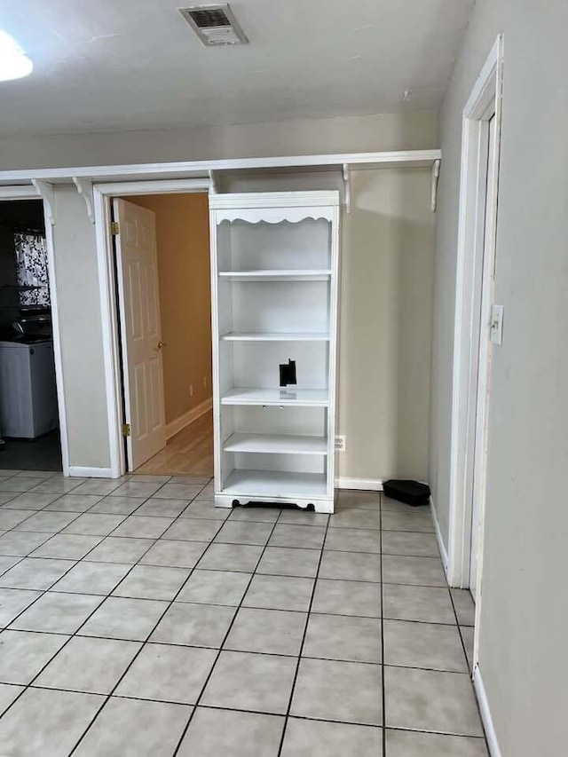 interior space with light tile patterned floors, baseboards, visible vents, and a closet