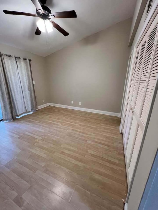 unfurnished bedroom with a ceiling fan, a closet, light wood-style flooring, and baseboards