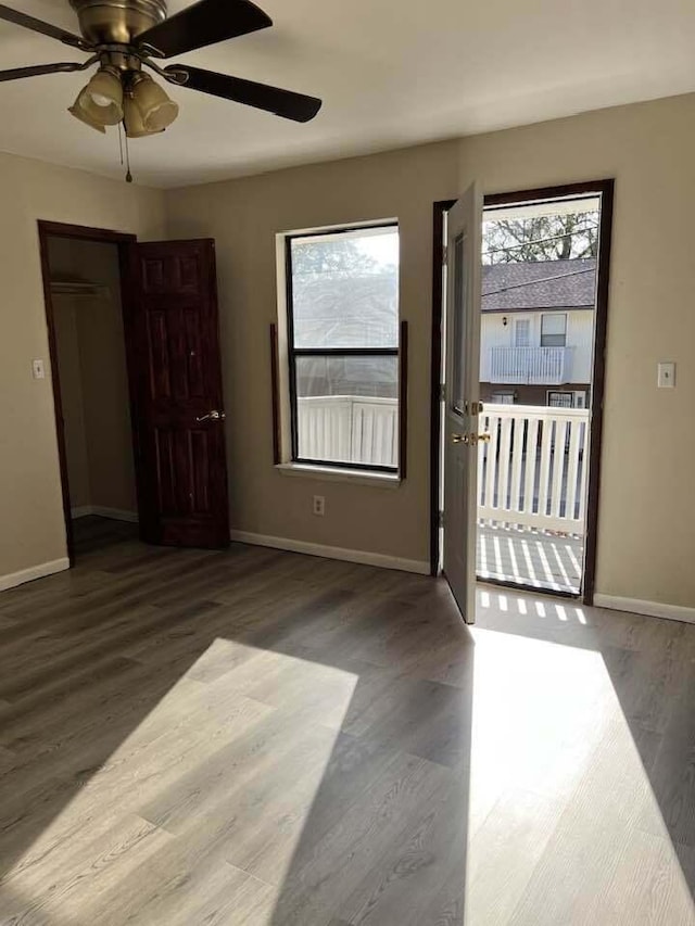 spare room with baseboards, ceiling fan, wood finished floors, and a healthy amount of sunlight