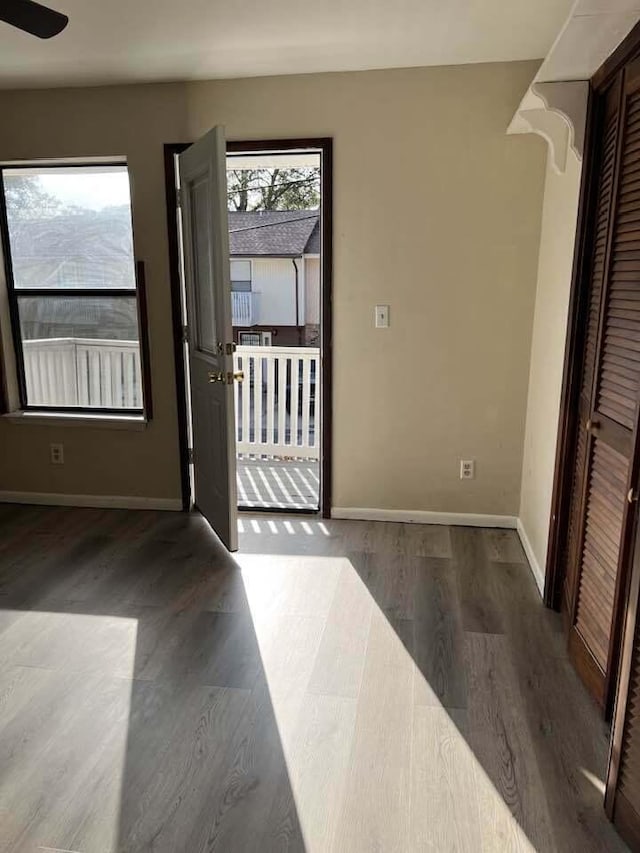 doorway with ceiling fan, wood finished floors, and baseboards