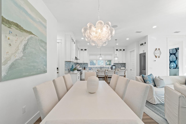 dining room with wood-type flooring, sink, and a chandelier