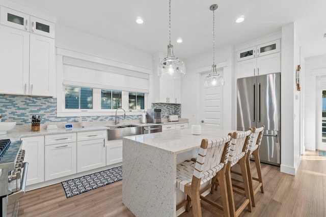 kitchen with white cabinetry, stainless steel appliances, a center island, and sink